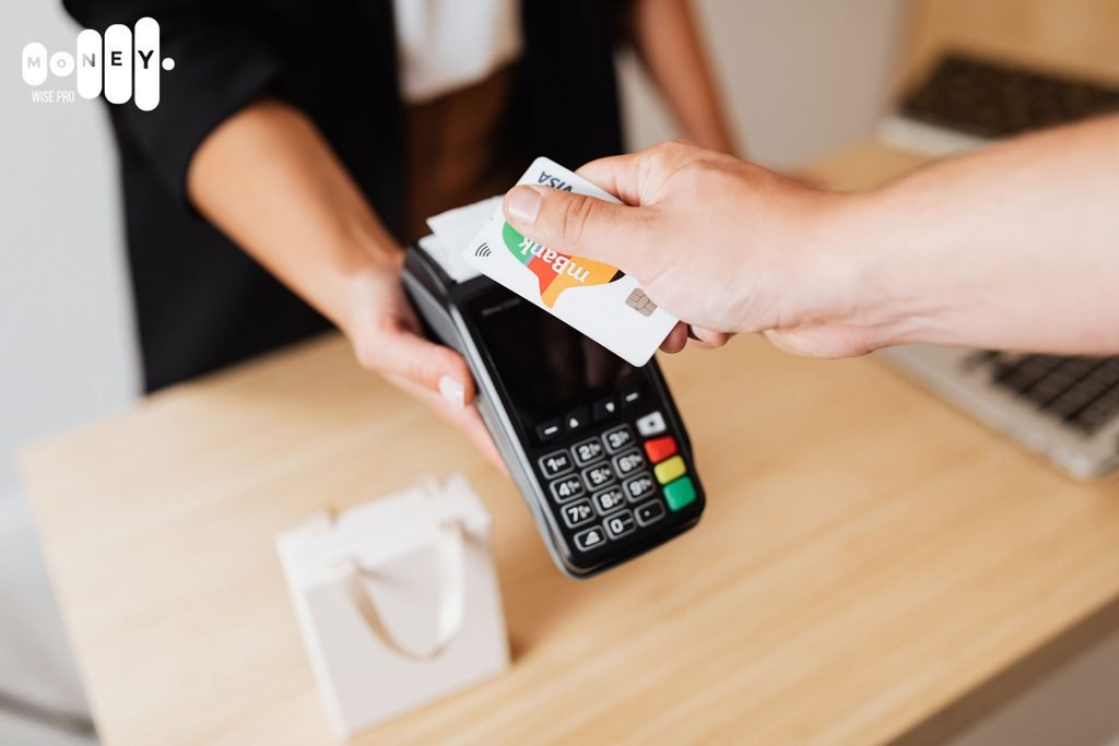 Hand holding a debit card at a checkout terminal during a purchase