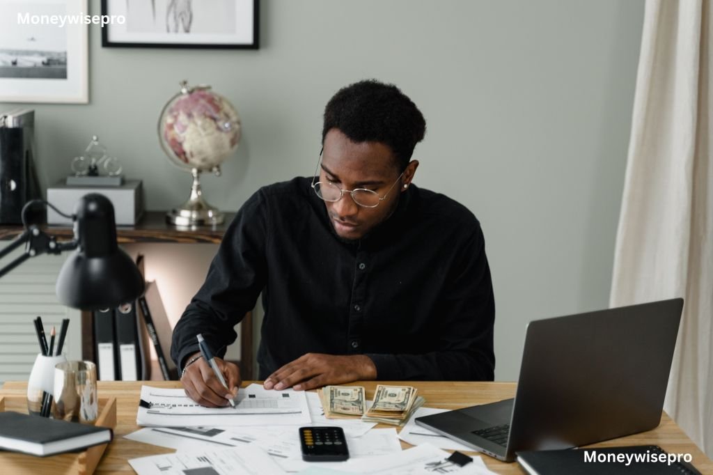  A man reviewing tax withholding paperwork with a calculator on a table at home