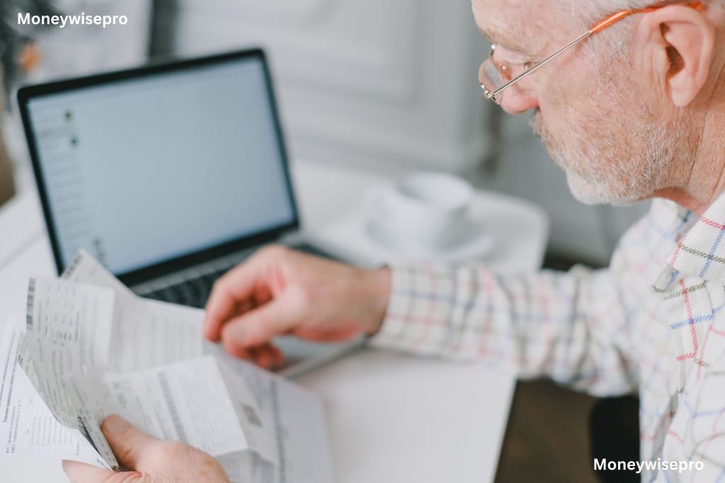 A person in glasses reviews a long grocery receipt at a home table with a laptop beside it