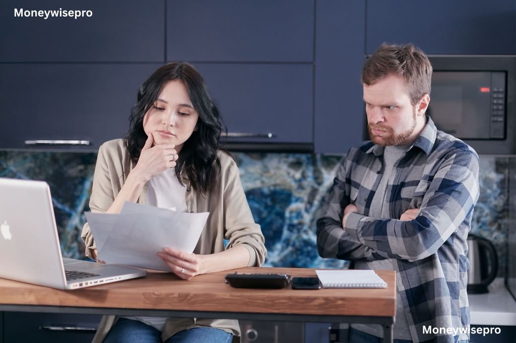 Couple sitting at kitchen table reviewing mortgage paperwork and laptop together closely