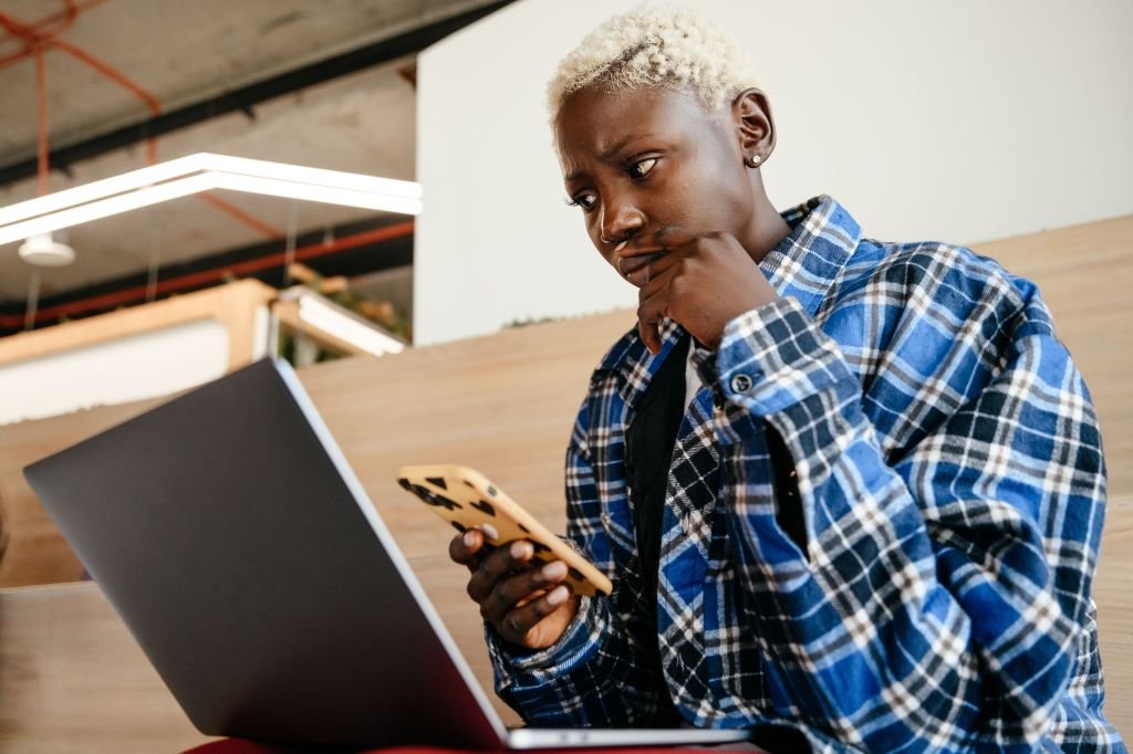 Person looking worried and concerned while checking bank account balance on phone while working