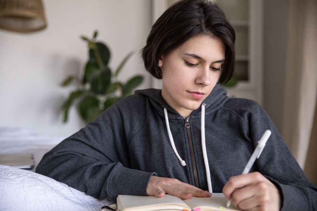 calm person writing in a notebook with a pen