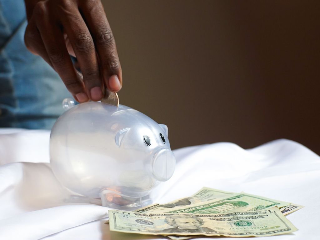 Person making conscious decision to save money in piggy bank or emergency fund