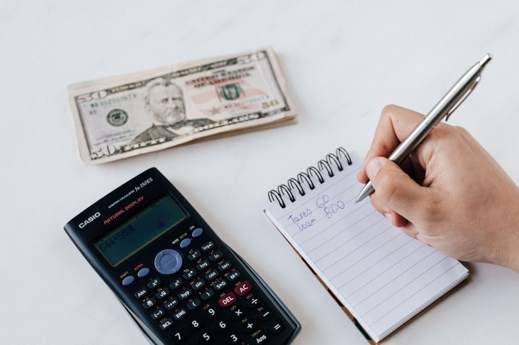 A person writing down their finances in a notebook to face the numbers honestly