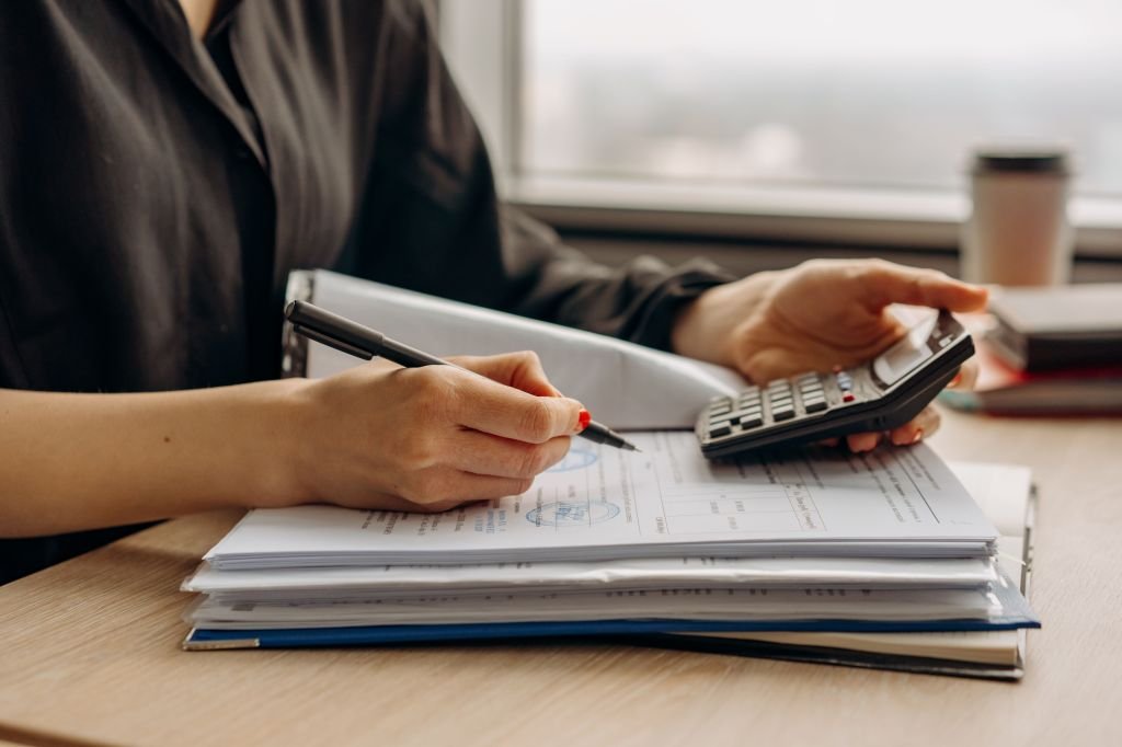 "Person reviewing bills and using a calculator at home