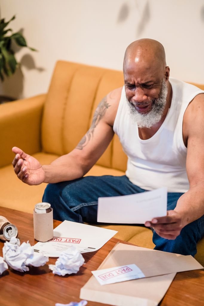 Person managing multiple bills and financial statements, feeling overwhelmed by debt obligations