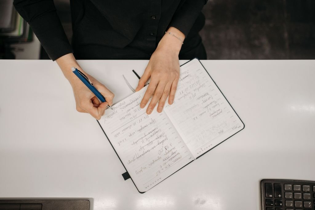 Person calmly writing shopping list or budget at desk